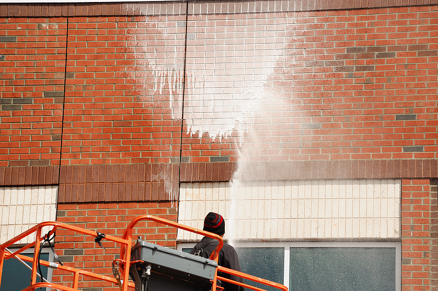 outdoor worker cleaning the exterior wall of building through pressure water