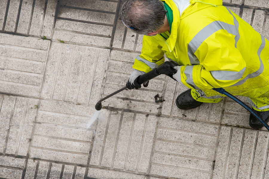 worker cleaning the sidewalk with pressurized water. maintenance or cleaning concept